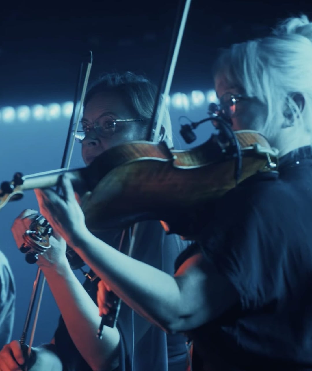 Two musicians play violins on a dark stage, illuminated by blue and red light. REDBULL SYMPHONIC by Chris Schwarz for RedBull — © EASYdoesit.